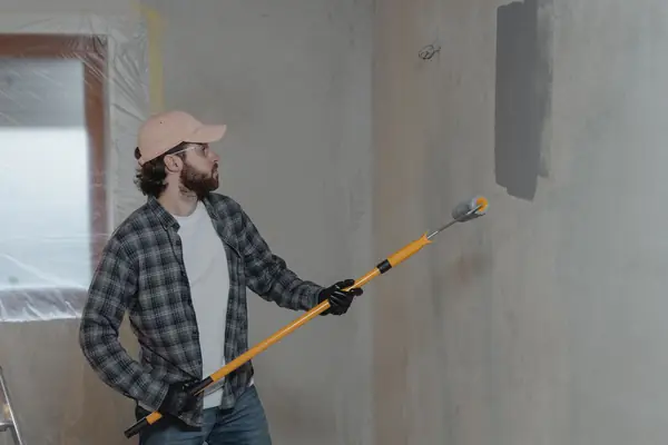 Painter rolling grey paint onto an interior wall in Norfolk